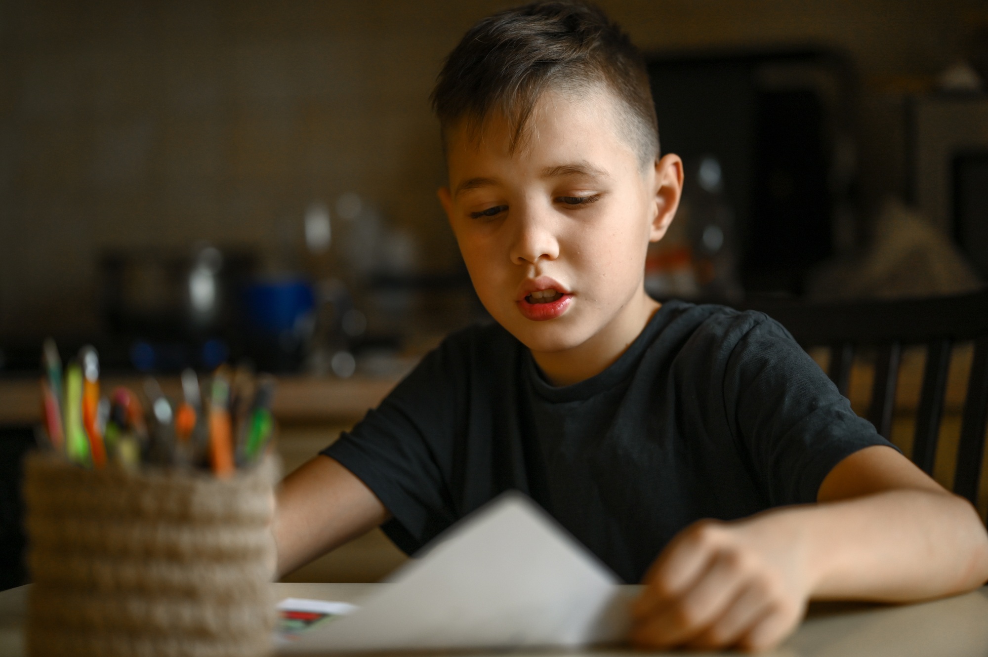 A 10-year-old boy draws a drawing with colored pencils