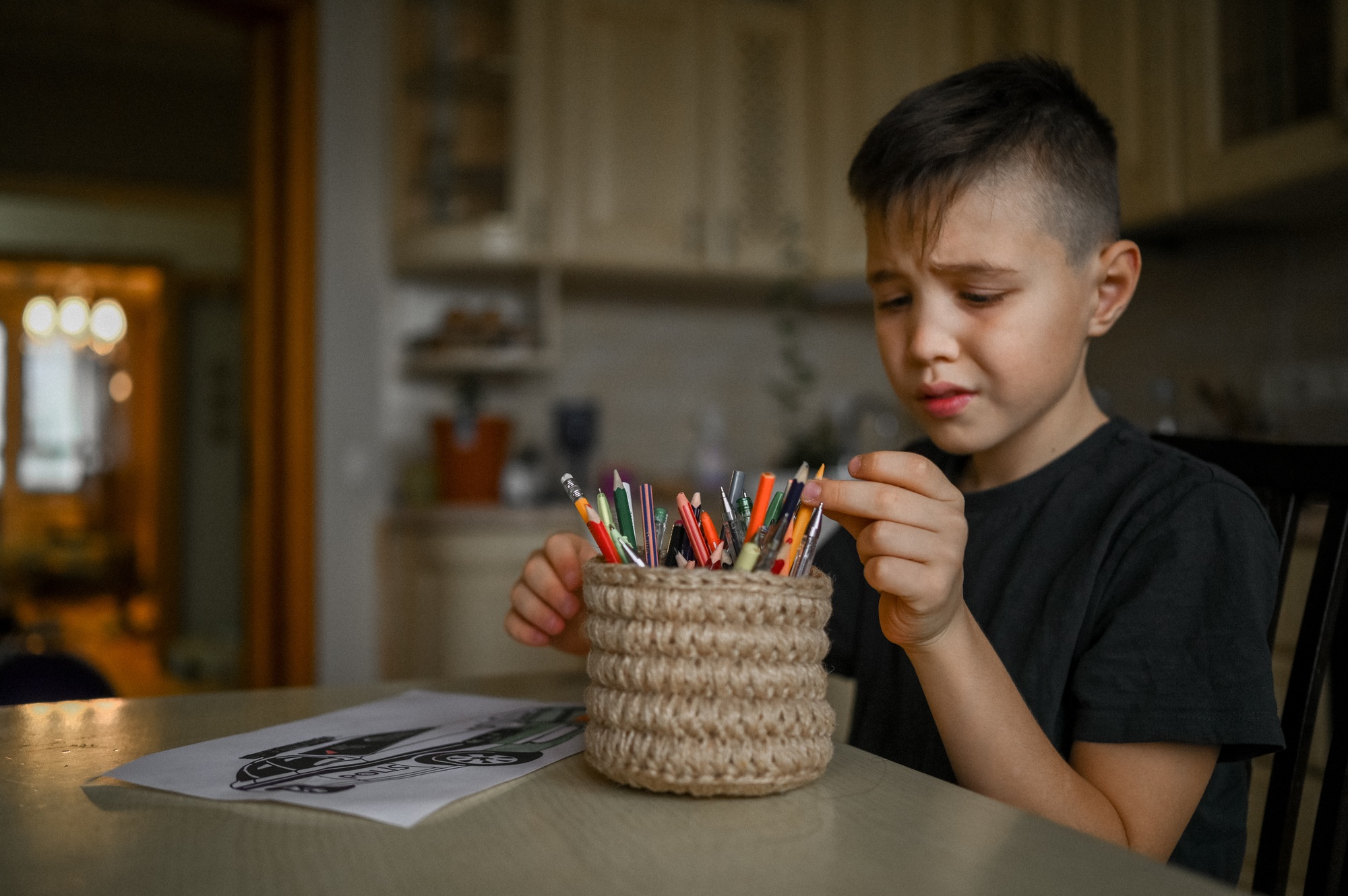 A 10-year-old boy draws a drawing with colored pencils