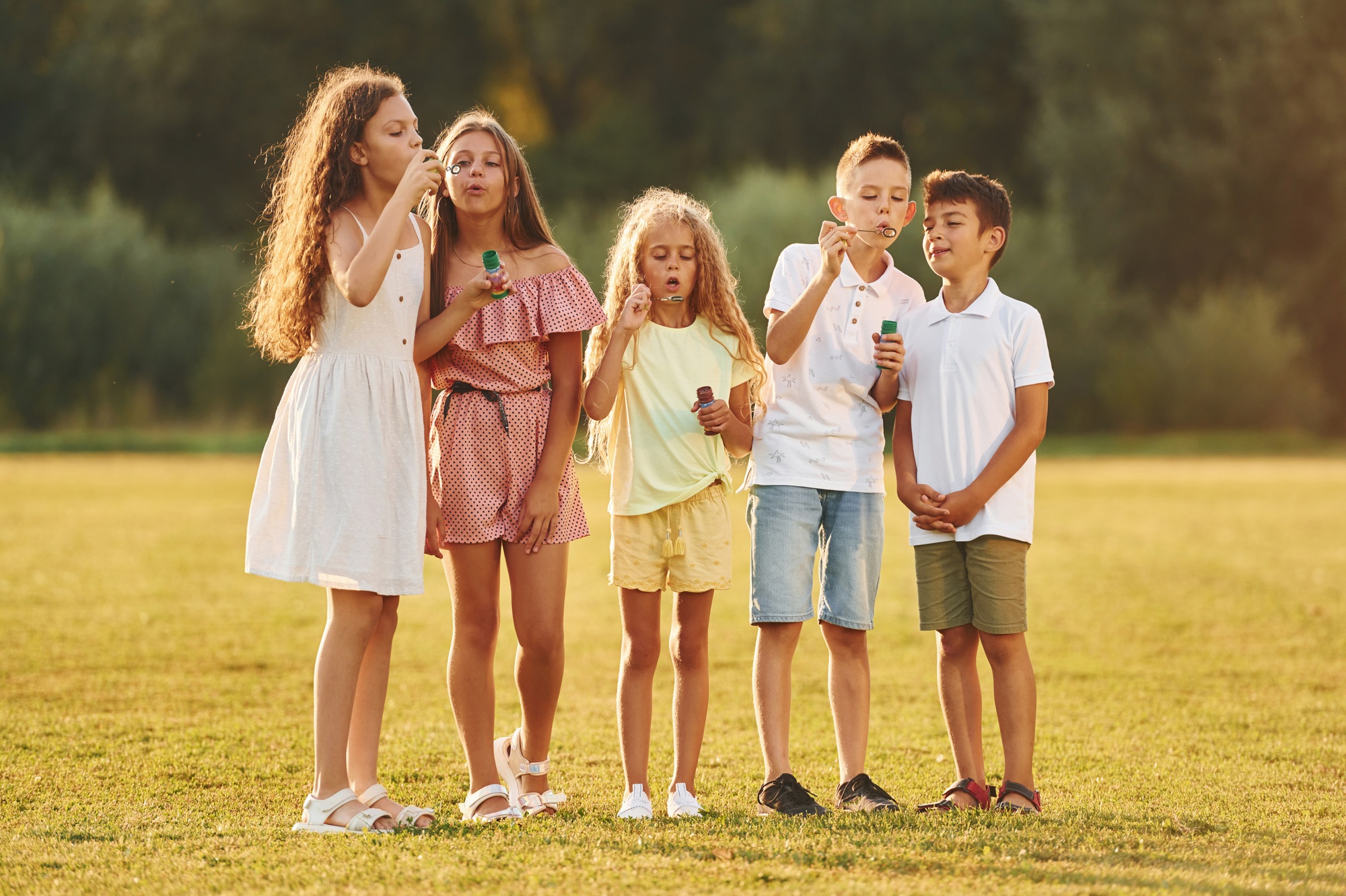 Beautiful sunlight. Group of happy kids is outdoors on the sportive field at daytime