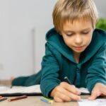 Boy drawing in on the floor a cozy room.