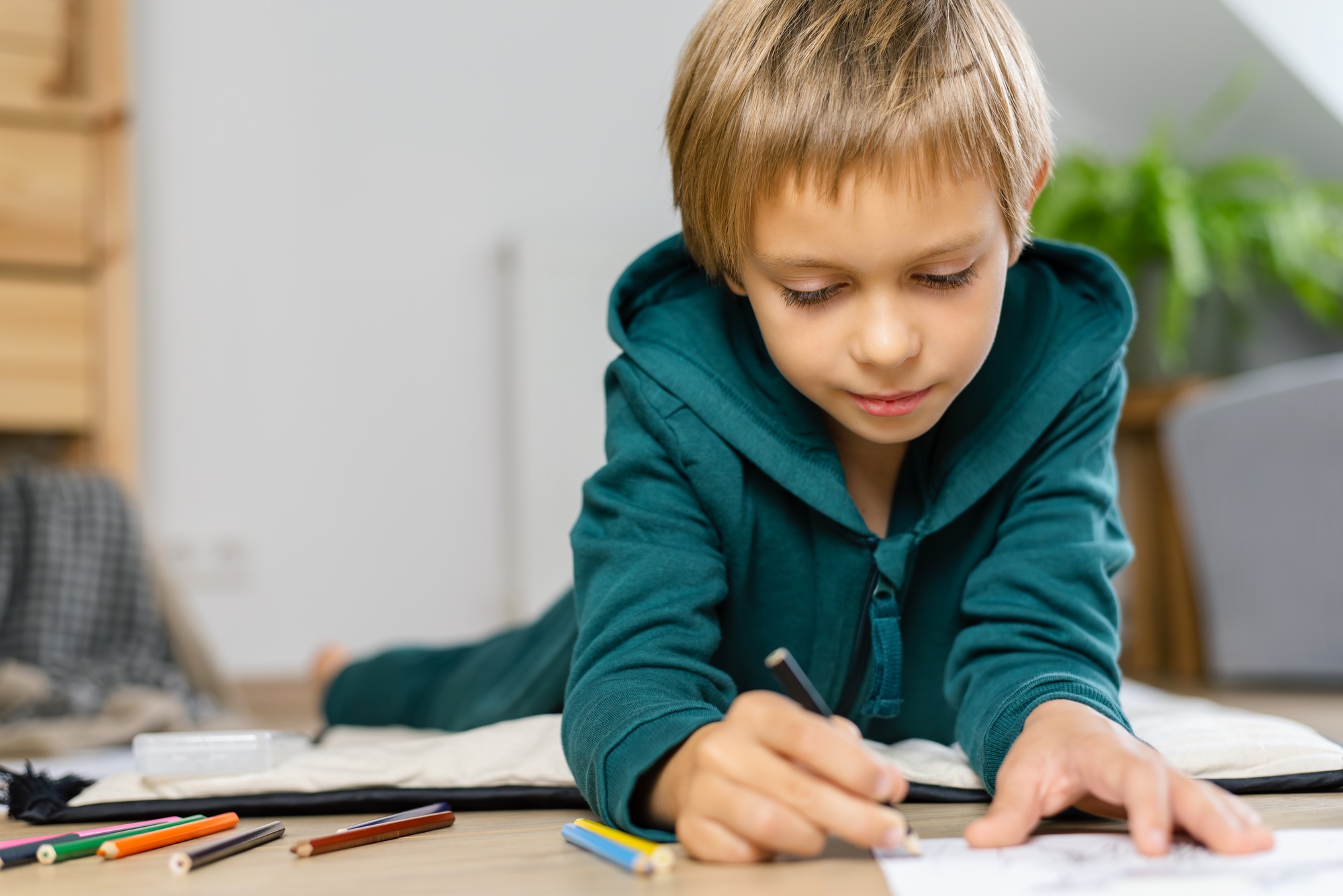 Boy drawing in on the floor a cozy room.