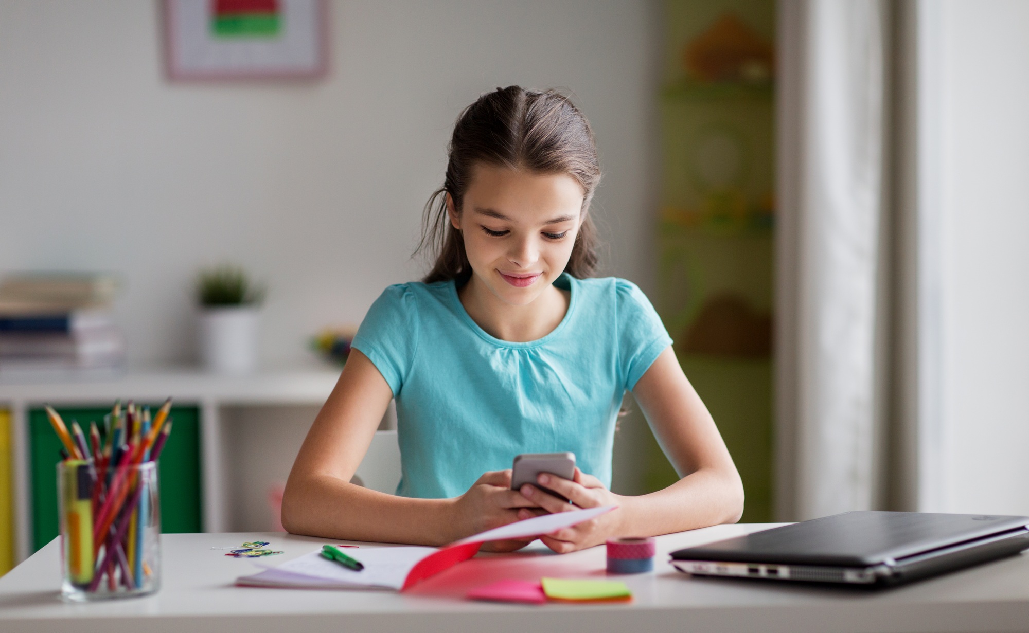 girl with smartphone distracting from homework
