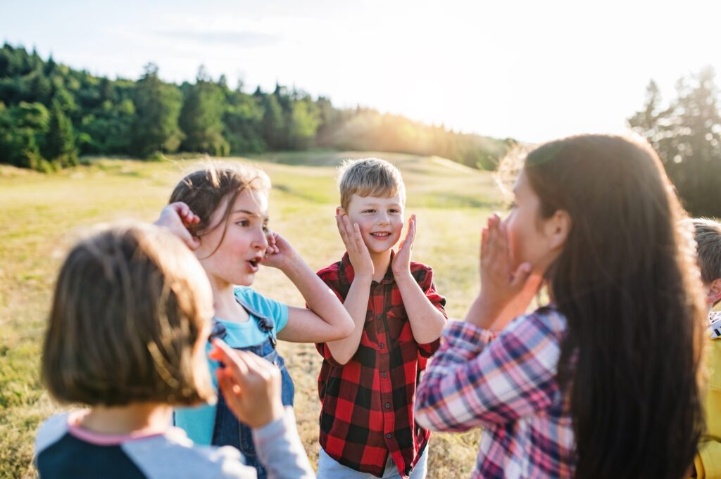 Group of school children standing on field trip in nature, playing