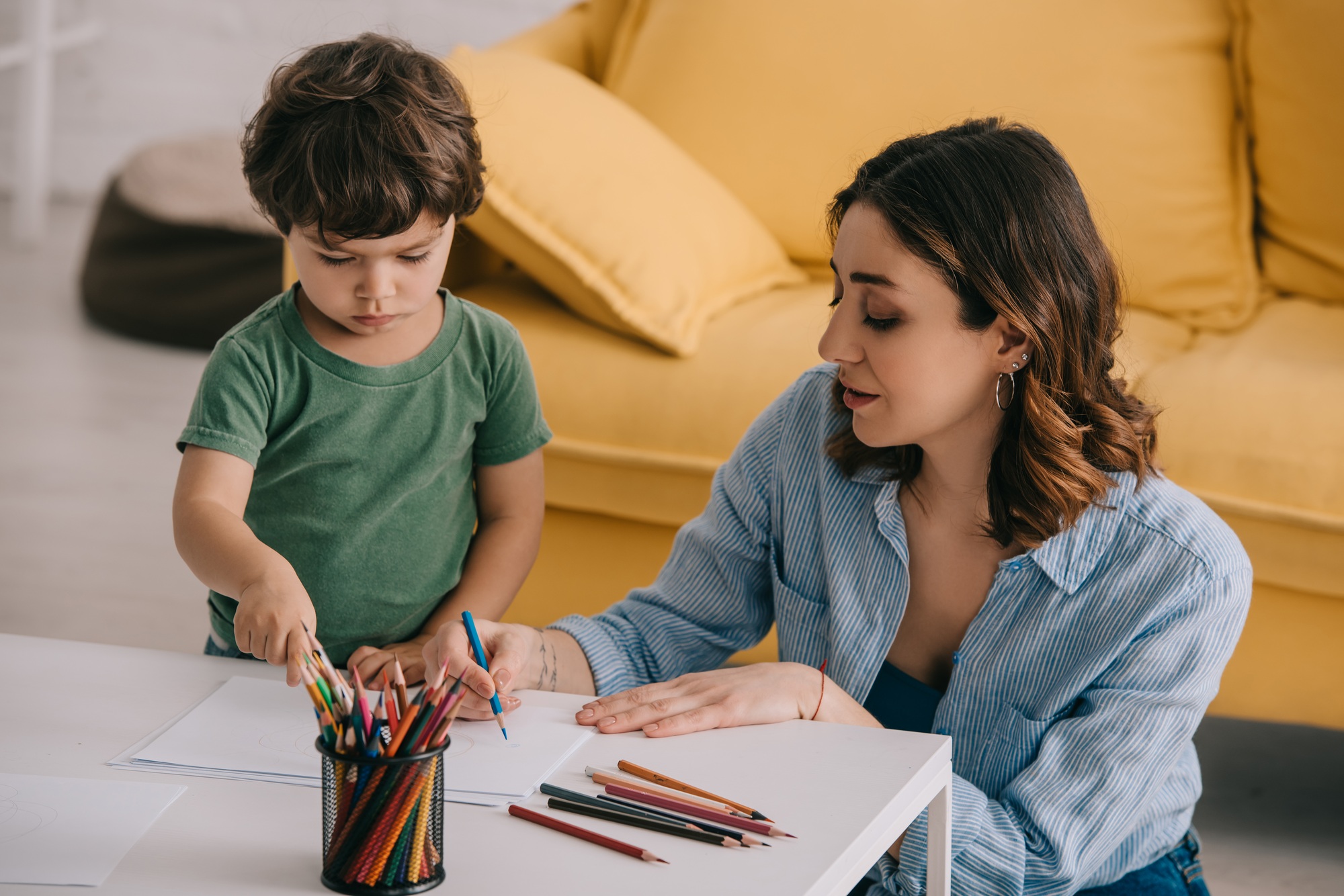 Mother and son drawing with color pencils in living room