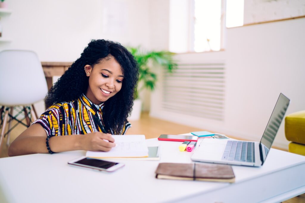 Smiling black teenager doing homework at home