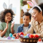 Smiling mother and kids wearing bunny ears painting easter eggs. Happy family celebration Easter
