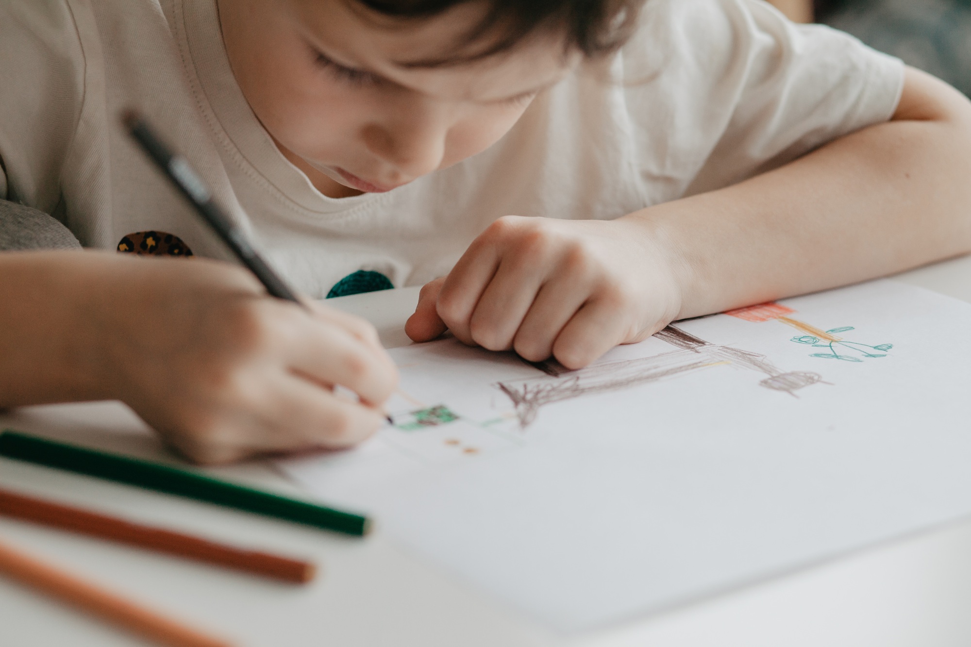 The boy draws with pencils at the kitchen