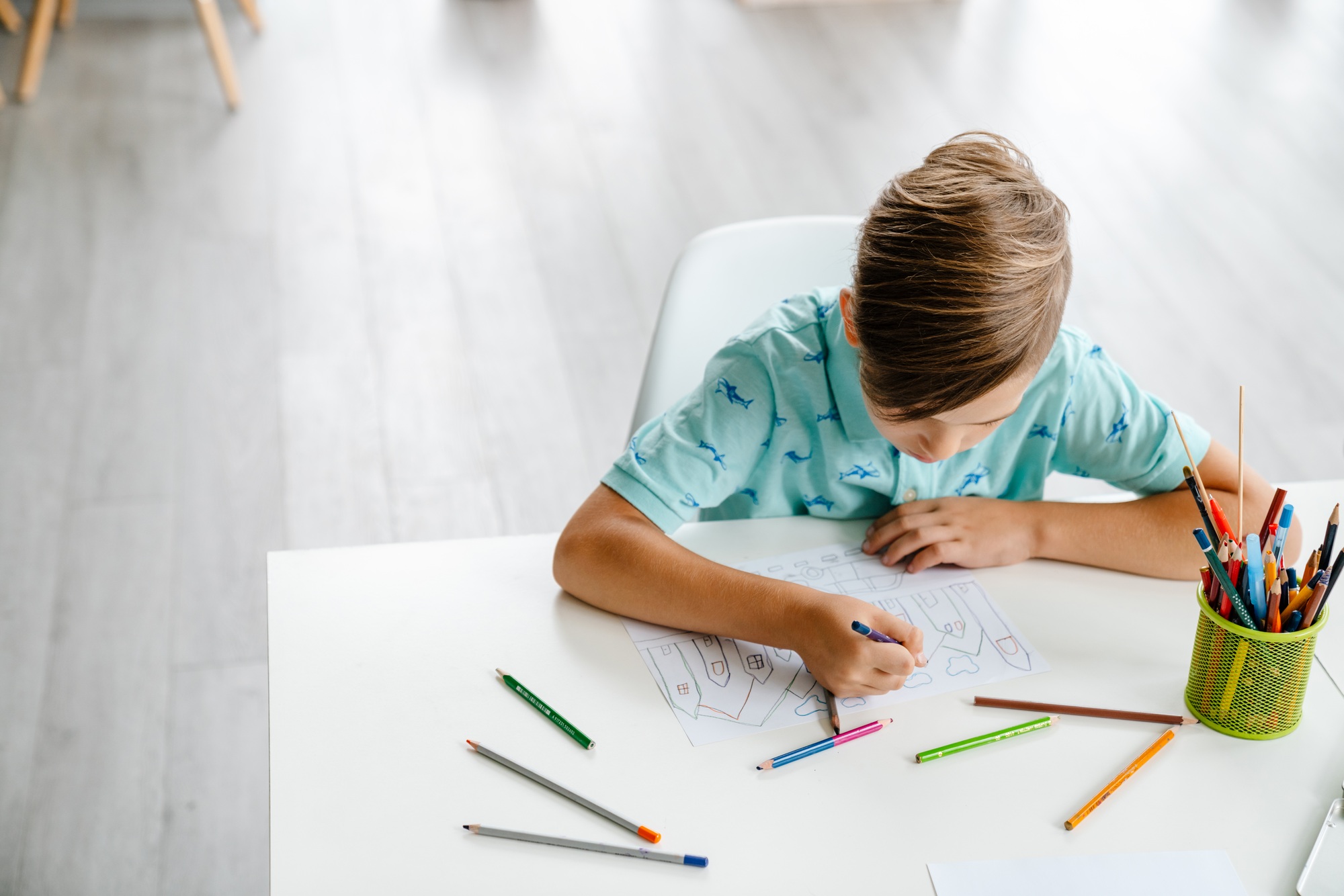White blond boy drawing during class in art school